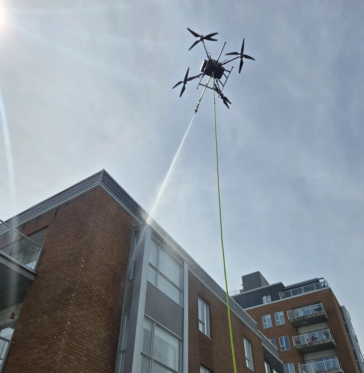 Drone H2O Drone nettoyant le haut d’un immeuble, avec son jet d’eau visible jusqu’à la façade